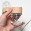 Frasco de perfume redondo de vidrio de 50 ml y 100 ml con tapa de madera