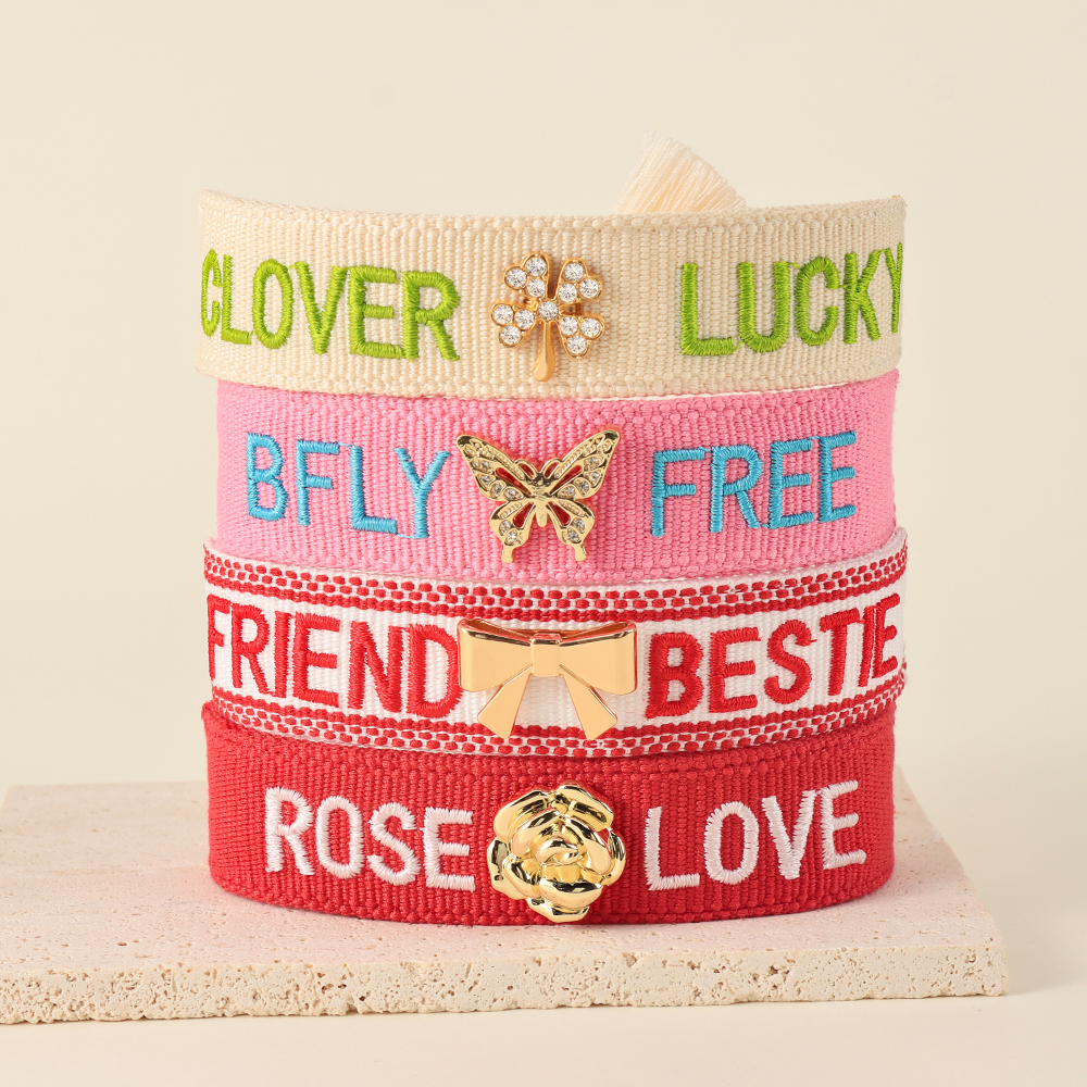 Tassel bracelets featuring embroidered words and decorative charms- rose, butterfly, clover, and bow