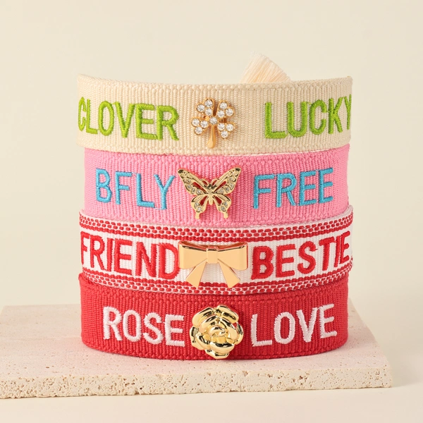 Tassel bracelets featuring embroidered words and decorative charms- rose, butterfly, clover, and bow