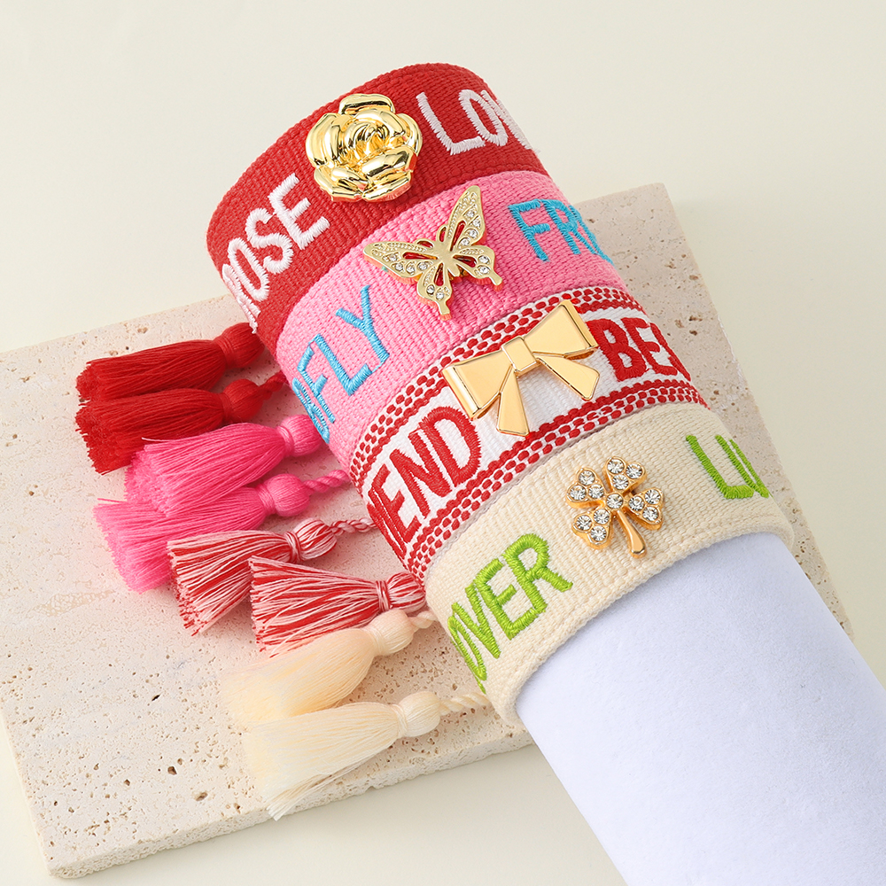 Tassel bracelets featuring embroidered words and decorative charms- rose, butterfly, clover, and bow